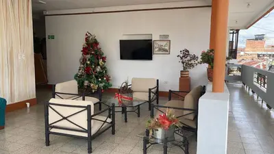 a living room with a christmas tree and a table and chairs at Hotel Tayrona in Puerto Berrío