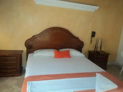 a bed with a wooden headboard and a red pillow at Hotel Tayrona in Puerto Berrío