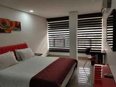 a bedroom with a bed and a desk and a window at Hotel Merlott 70 in Medellín