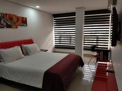 a bedroom with a bed with a red headboard and a window at Hotel Merlott 70 in Medellín