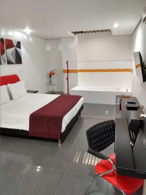 a bedroom with a large bed and a red chair at Hotel Merlott 70 in Medellín