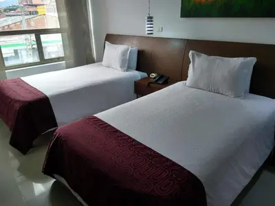 two beds sitting next to each other in a room at Hotel Merlott 70 in Medellín