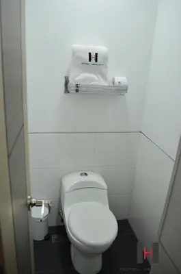 a bathroom with a toilet and a towel on a shelf at Hotel Merlott 70 in Medellín
