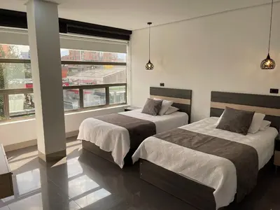 two beds in a room with two windows at Hotel Merlott 70 in Medellín