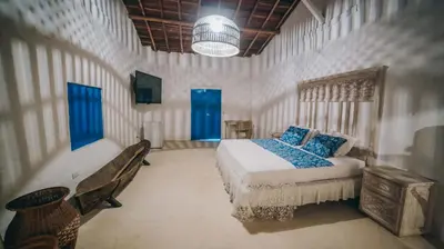a bedroom with a bed and a bench and blue doors at Ángel de Santa Fe by Bernalo Hotels in Santa Fe de Antioquia