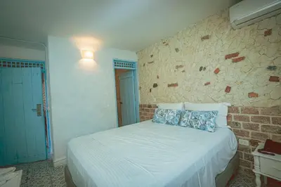 a bedroom with a white bed and a brick wall at Ángel de Santa Fe by Bernalo Hotels in Santa Fe de Antioquia