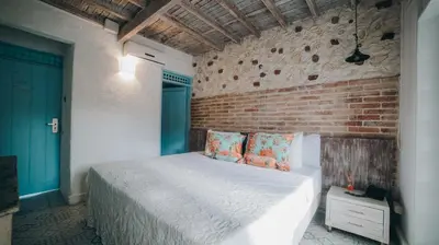 a bedroom with a white bed and a brick wall at Ángel de Santa Fe by Bernalo Hotels in Santa Fe de Antioquia