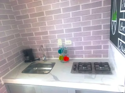 a kitchen counter with a sink and a pink brick wall at Casa de Luna in La Dorada