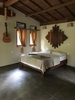 a bedroom with a bed and a guitar on the wall at Ritmo del Rio in San Rafael