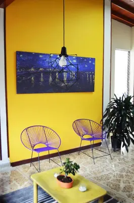 two chairs and a table in a room with a yellow wall at Buntes House-Casa Hotel Laureles-Estadio in Medellín