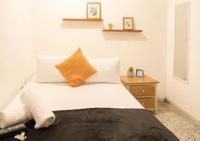 a bedroom with a white bed and a wooden nightstand at Buntes House-Casa Hotel Laureles-Estadio in Medellín