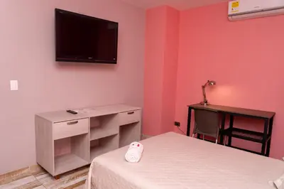 a bedroom with two beds and a tv on the wall at Hotel El Meson in La Dorada