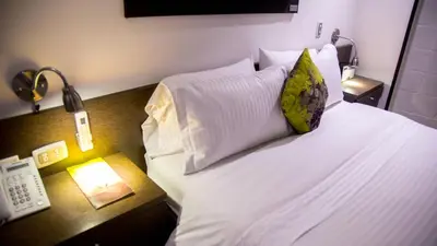 a bedroom with a bed with a phone and a lamp at Hotel Golden Palermo in Medellín