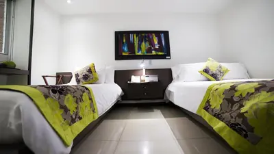 a bedroom with two beds and a tv on the wall at Hotel Golden Palermo in Medellín