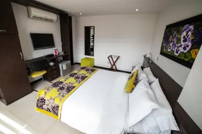 a bedroom with a large white bed and a tv at Hotel Golden Palermo in Medellín