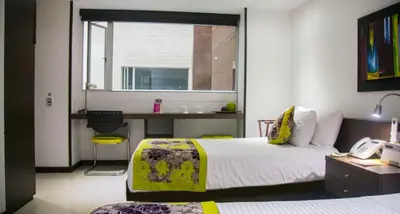 a bedroom with a bed and a desk with a phone at Hotel Golden Palermo in Medellín