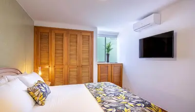 a bedroom with a bed and a flat screen tv at Alcazar de Oviedo by EE Hoteles in Medellín