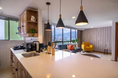 a kitchen with two sinks and a living room at Alcazar de Oviedo by EE Hoteles in Medellín