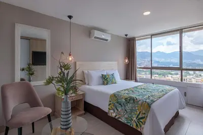a bedroom with a bed and a chair and a window at Alcazar de Oviedo by EE Hoteles in Medellín