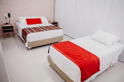two beds in a room with white and red at Hotel Sie7e in Medellín