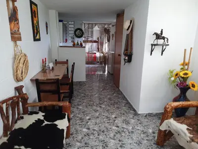 a dining room with a table and chairs and a kitchen at Apartamento Campestre Medellin in Medellín