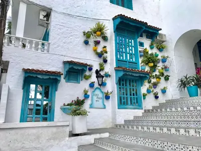 a white building with blue windows and stairs at CABAÑA 1 LA ALDEA in Doradal