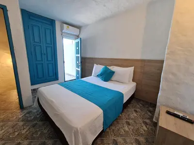 a bedroom with a large bed with a blue door at CABAÑA 1 LA ALDEA in Doradal