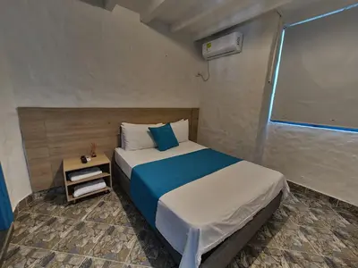 a bedroom with a bed with a blue and white blanket at CABAÑA 1 LA ALDEA in Doradal