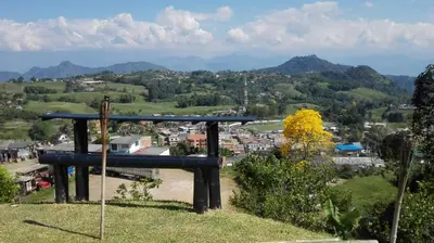 a bench on top of a hill overlooking a city at Alojamiento Campestre Cabañas Mirador Ingrumá Riosucio Caldas in Ruiosucio