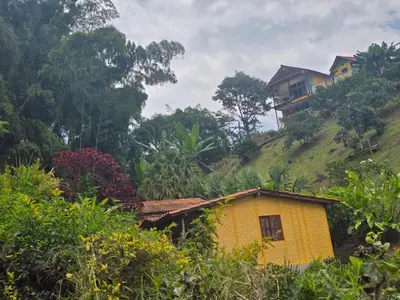 a yellow house on a hill with a house on it at Alojamiento Campestre Cabañas Mirador Ingrumá Riosucio Caldas in Ruiosucio