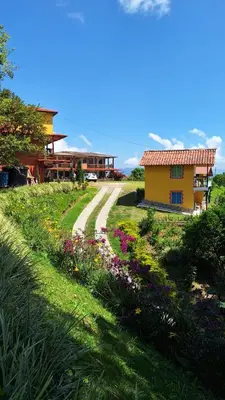 a house with a road next to a field of flowers at Alojamiento Campestre Cabañas Mirador Ingrumá Riosucio Caldas in Ruiosucio