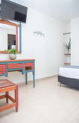 a room with a bed and a desk and a tv at Hotel Conquistadores in Medellín