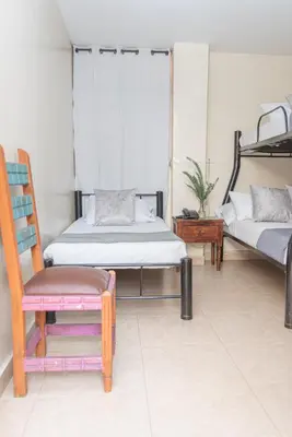 a room with two beds and a chair and a table at Hotel Conquistadores in Medellín