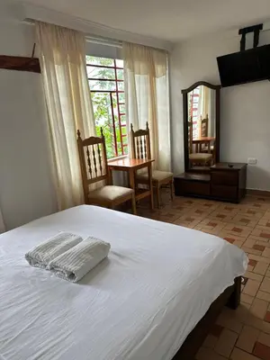 a bedroom with a white bed and a table and chairs at Eco Lodge La Juanita in Manizales