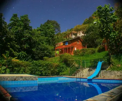 a house on top of a hill with a swimming pool at Eco Lodge La Juanita in Manizales