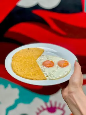 a person holding a plate of food with eggs and chips at Rock Hostel Medellin in Medellín