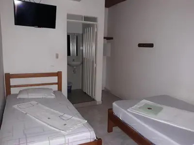 two beds in a room with a tv on the wall at HOTEL LA QUINTA in La Dorada