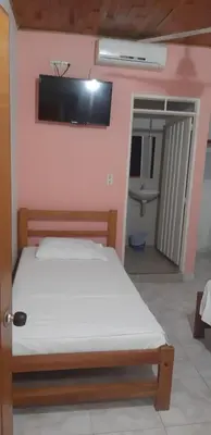 a bedroom with a bed and a bathroom with a sink at HOTEL LA QUINTA in La Dorada