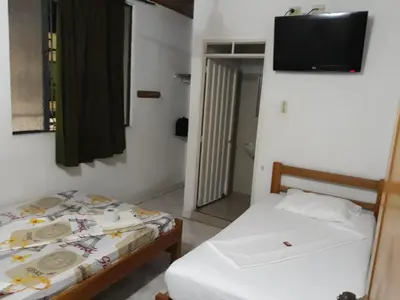 a bedroom with two beds and a television on the wall at HOTEL LA QUINTA in La Dorada