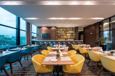 a restaurant with wooden tables and yellow chairs at Hotel Estelar Square in Medellín