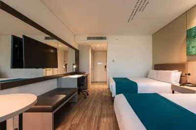 a hotel room with two beds and a desk at Hotel Estelar Square in Medellín