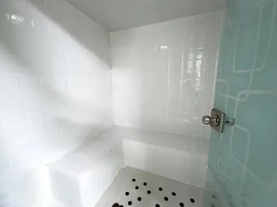 a bathroom with a shower with white tiles at Hotel Bolivariana Plaza Medellin in Medellín