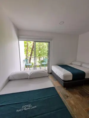 two beds in a room with a window at Hotel Puerto Triunfo in Doradal