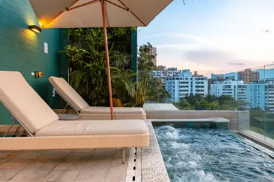 a balcony with a hot tub and chairs and an umbrella at Celestino Boutique Hotel & Spa in Medellín