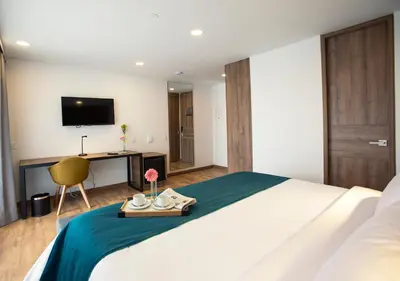 a hotel room with a bed with a desk and a tv at Hotel Lagoon in Rionegro