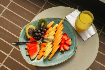 a plate of fruit and vegetables and a glass of orange juice at Hotel Lagoon in Rionegro