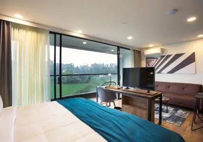 a bedroom with a bed and a desk with a television at Hotel Lagoon in Rionegro