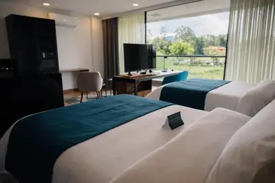 a hotel room with two beds and a television at Hotel Lagoon in Rionegro