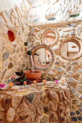 a stone wall with three mirrors and a sink at Hospedaje Solentiname in Medellín