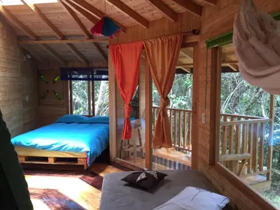 a bedroom in a log cabin with a bed and windows at Hospedaje Solentiname in Medellín
